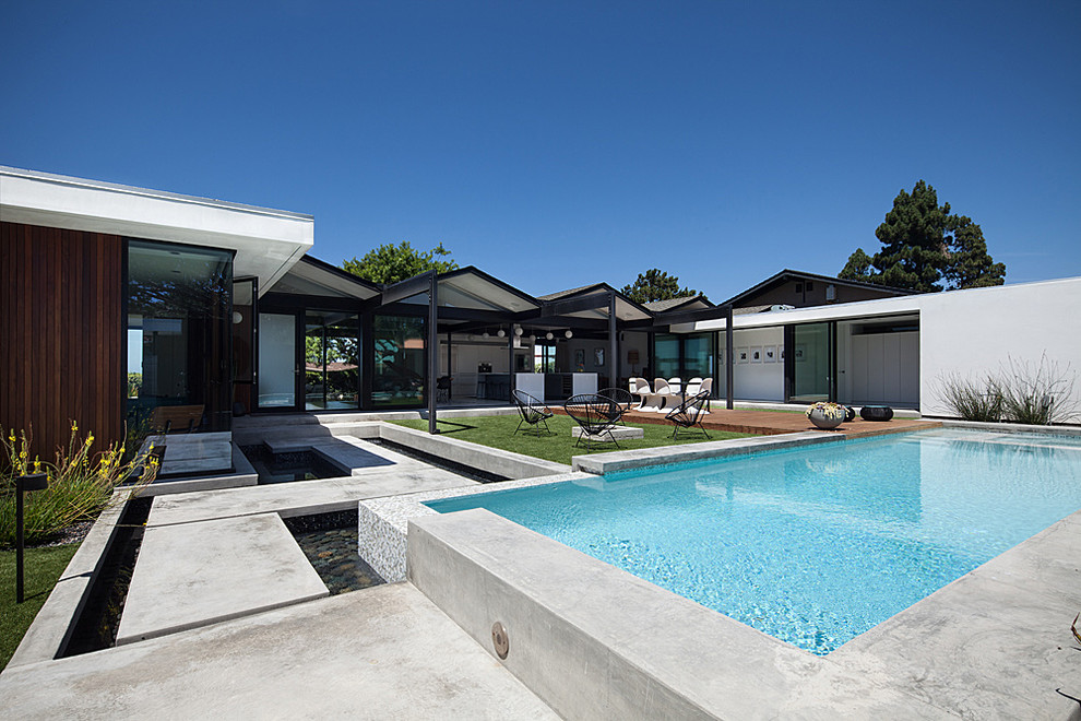 Immagine di una piscina monocorsia minimalista rettangolare di medie dimensioni e dietro casa con lastre di cemento