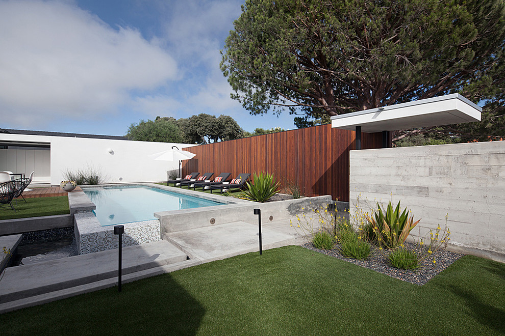 Foto de piscina alargada moderna de tamaño medio rectangular en patio trasero con losas de hormigón