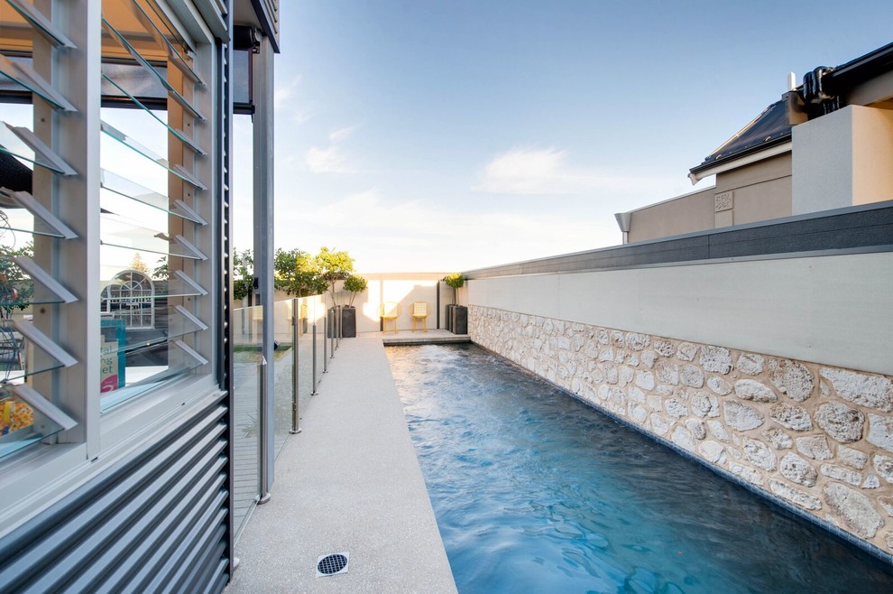Imagen de piscina alargada minimalista grande rectangular en patio lateral con suelo de hormigón estampado