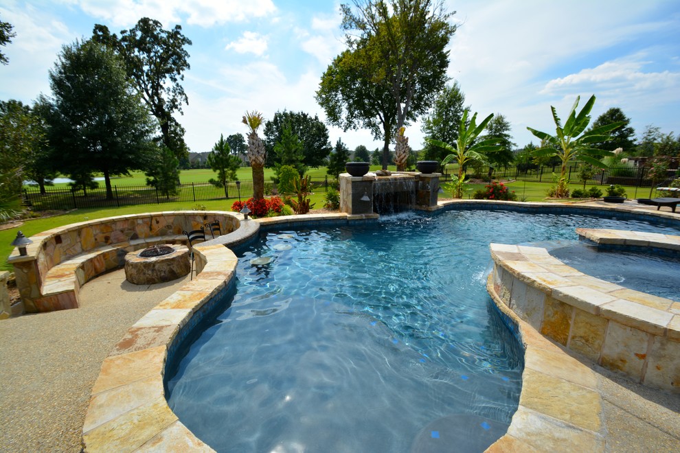 Immagine di un'ampia piscina monocorsia tropicale personalizzata dietro casa con una vasca idromassaggio e pavimentazioni in pietra naturale