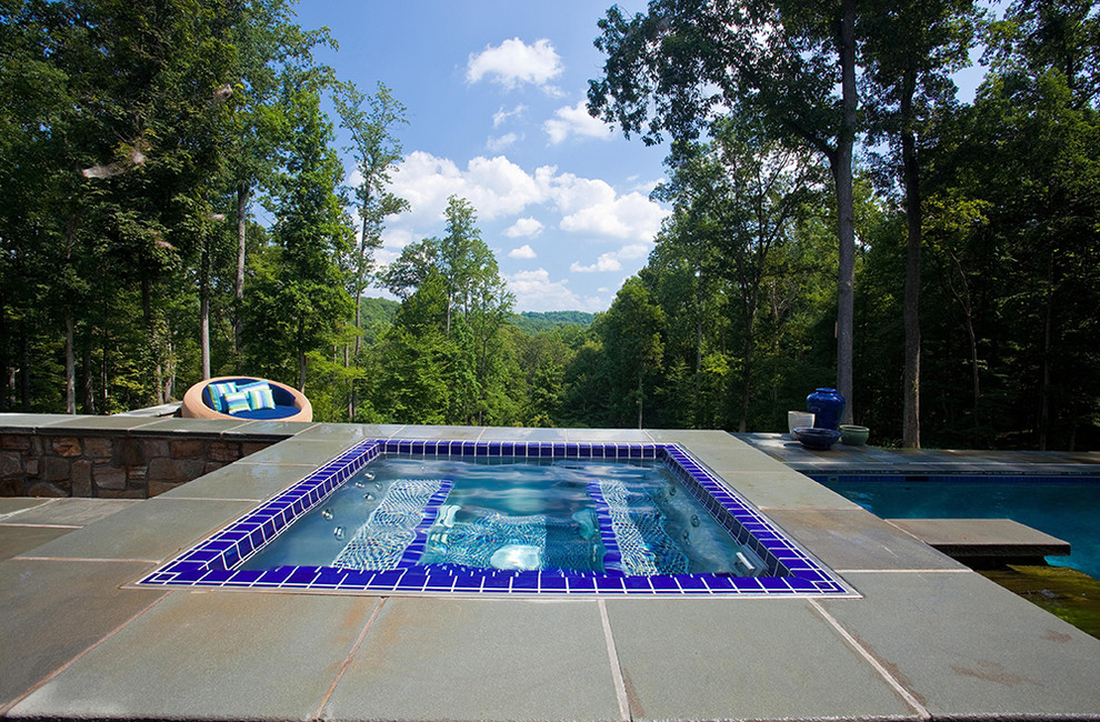 Immagine di una piscina monocorsia chic rettangolare dietro casa con una vasca idromassaggio e pavimentazioni in pietra naturale