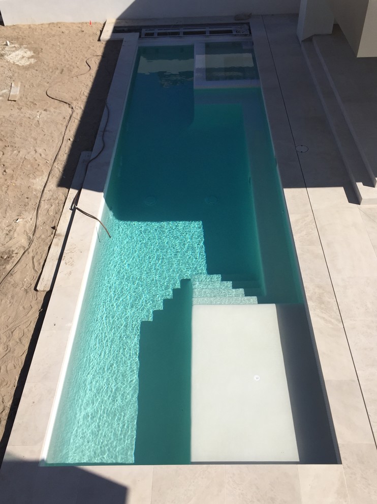 Foto de piscinas y jacuzzis infinitos actuales grandes rectangulares en patio delantero con losas de hormigón