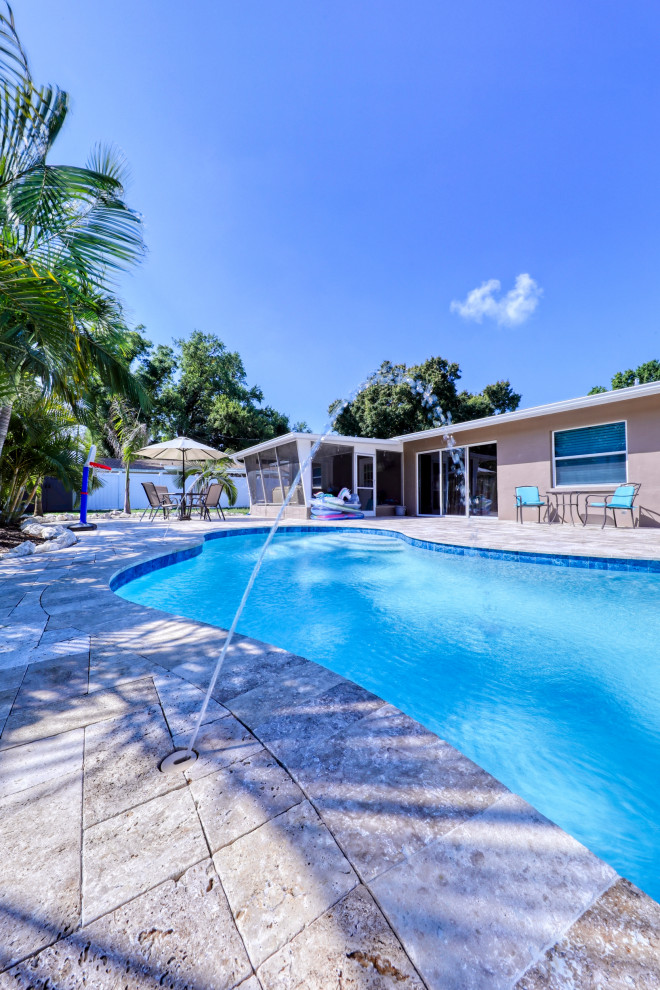 Foto di una piscina naturale tropicale personalizzata di medie dimensioni e dietro casa con pavimentazioni in pietra naturale