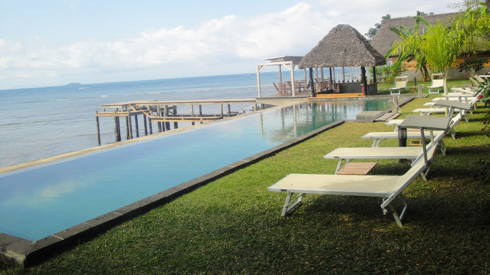 Modelo de piscina infinita tropical grande rectangular con suelo de hormigón estampado