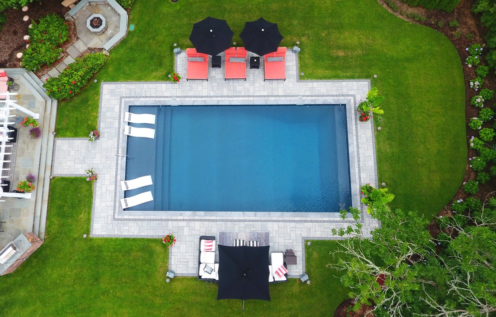 Идея дизайна: большой прямоугольный бассейн на заднем дворе с мощением тротуарной плиткой