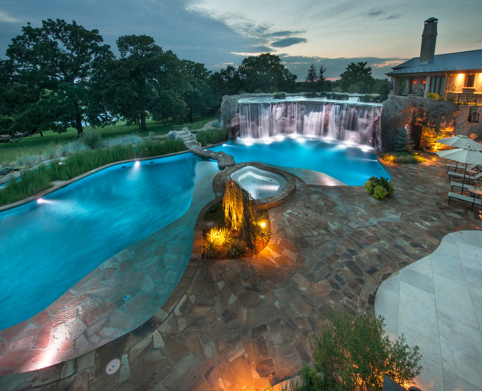 Aménagement d'une très grande piscine naturelle et arrière éclectique sur mesure avec un point d'eau et des pavés en pierre naturelle.