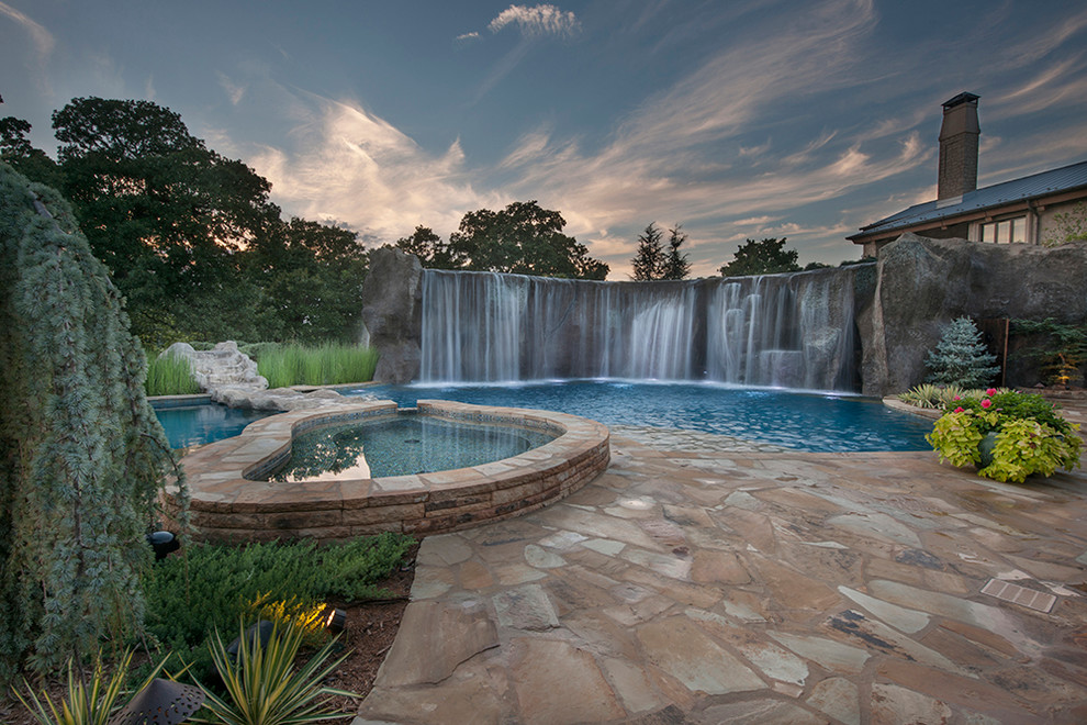 Идея дизайна: огромный естественный бассейн произвольной формы на заднем дворе в стиле фьюжн с фонтаном и покрытием из каменной брусчатки