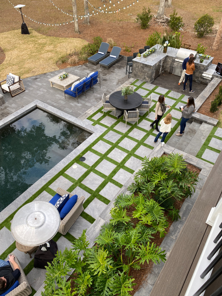 Modelo de piscina natural costera extra grande rectangular en patio trasero con adoquines de ladrillo
