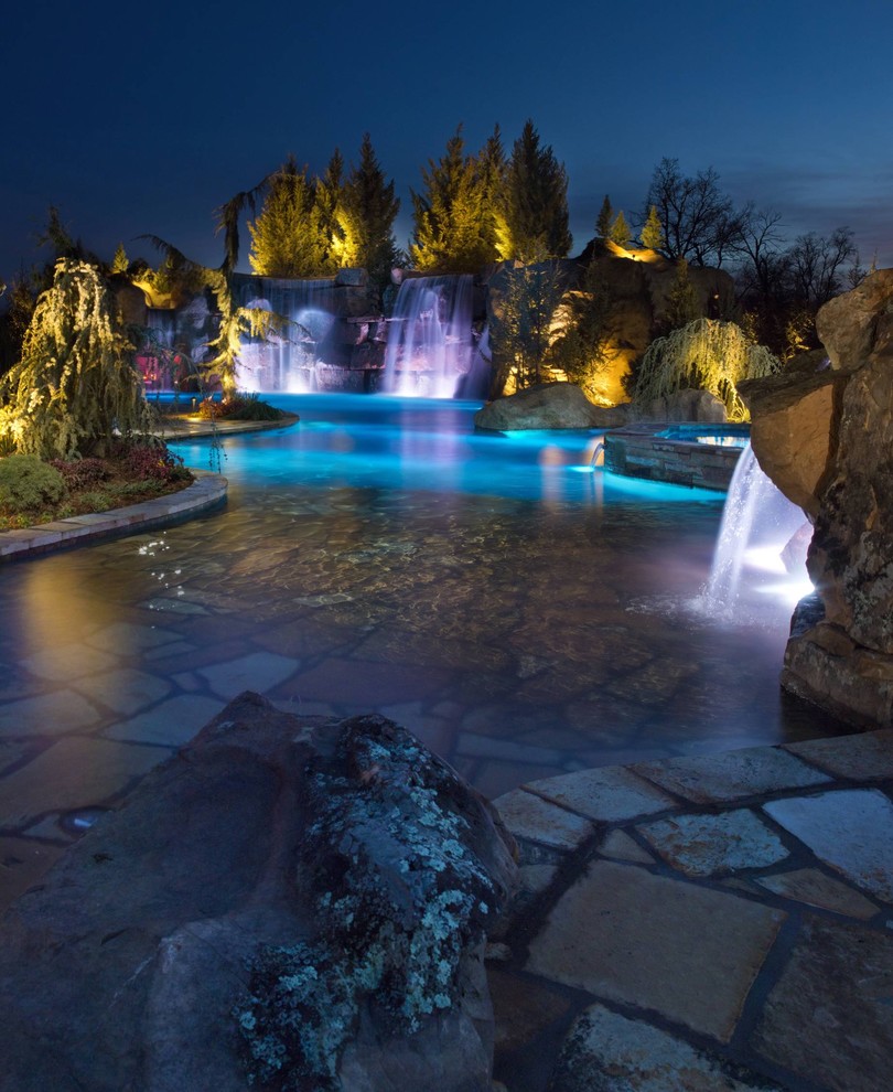 Cette image montre une très grande piscine naturelle et arrière chalet sur mesure avec un point d'eau et des pavés en pierre naturelle.