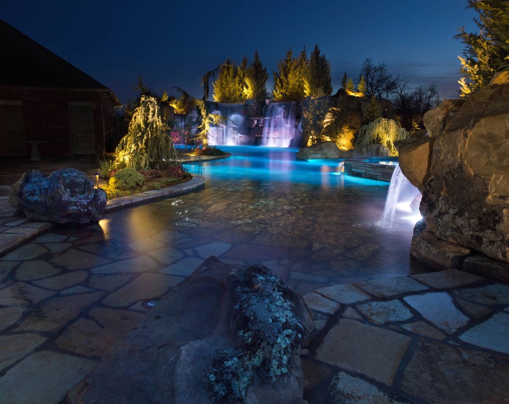 Ejemplo de piscina con fuente natural rústica extra grande a medida en patio trasero con adoquines de piedra natural