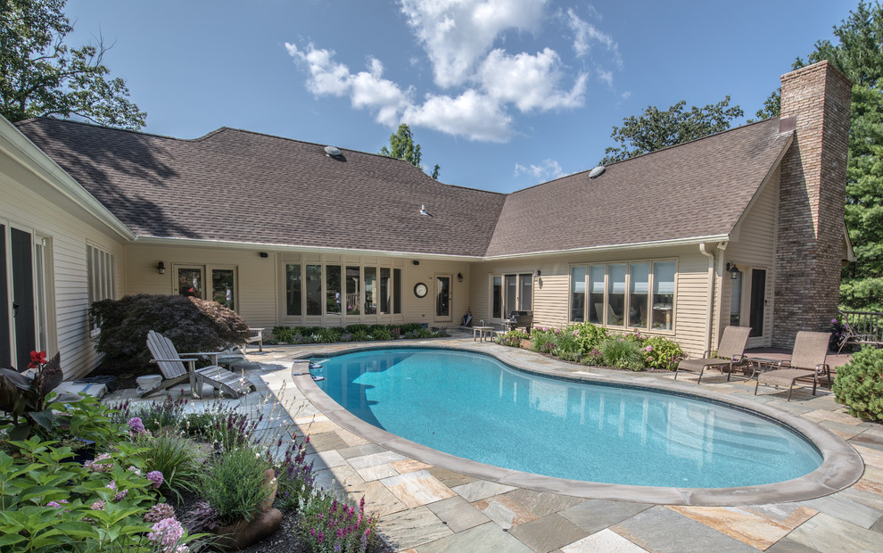 Foto de piscinas y jacuzzis alargados clásicos grandes tipo riñón en patio trasero con suelo de baldosas