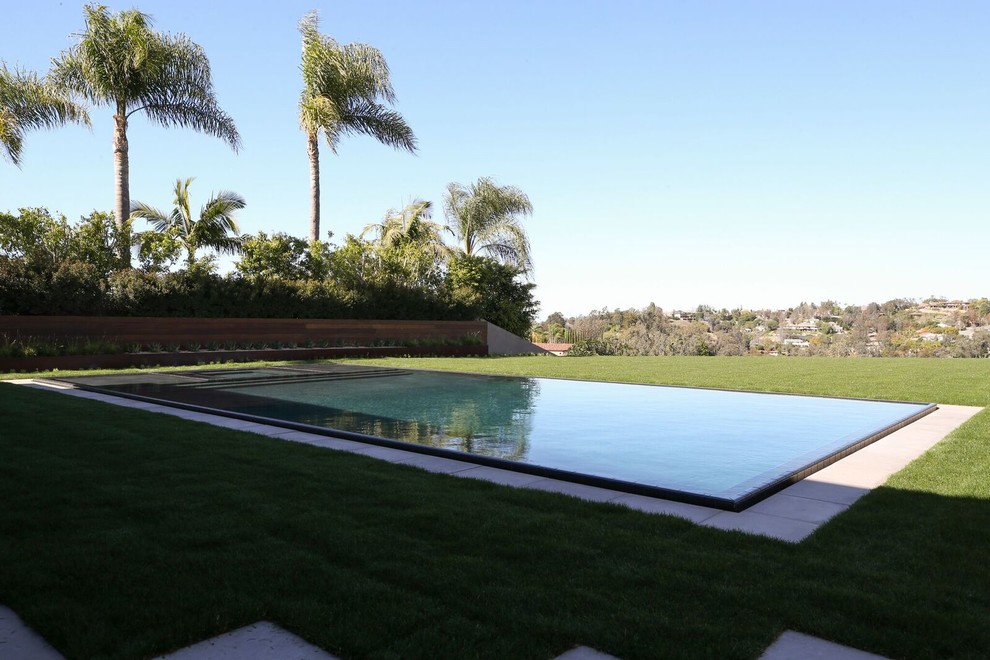 Imagen de piscinas y jacuzzis infinitos contemporáneos grandes rectangulares en patio trasero con adoquines de hormigón