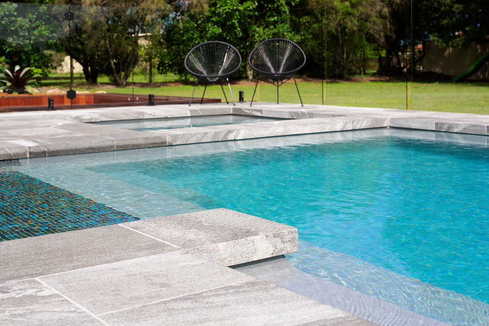 Foto di una grande piscina monocorsia design rettangolare dietro casa con pavimentazioni in pietra naturale
