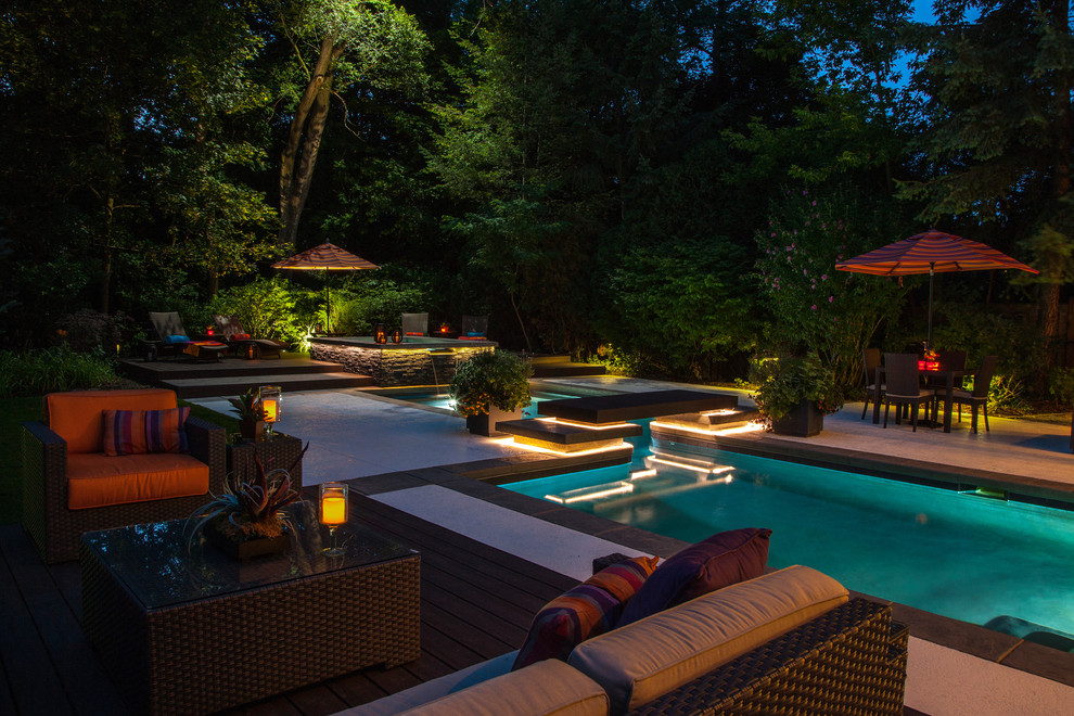 Imagen de piscinas y jacuzzis alargados de tamaño medio en forma de L en patio trasero con adoquines de piedra natural