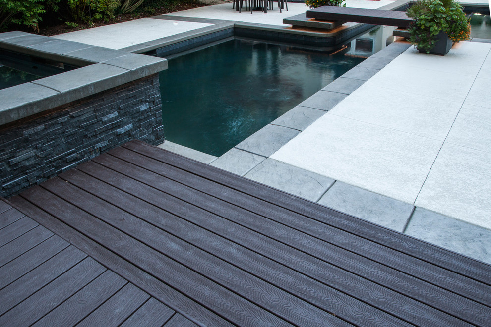 Diseño de piscinas y jacuzzis alargados de tamaño medio en forma de L en patio trasero con adoquines de piedra natural