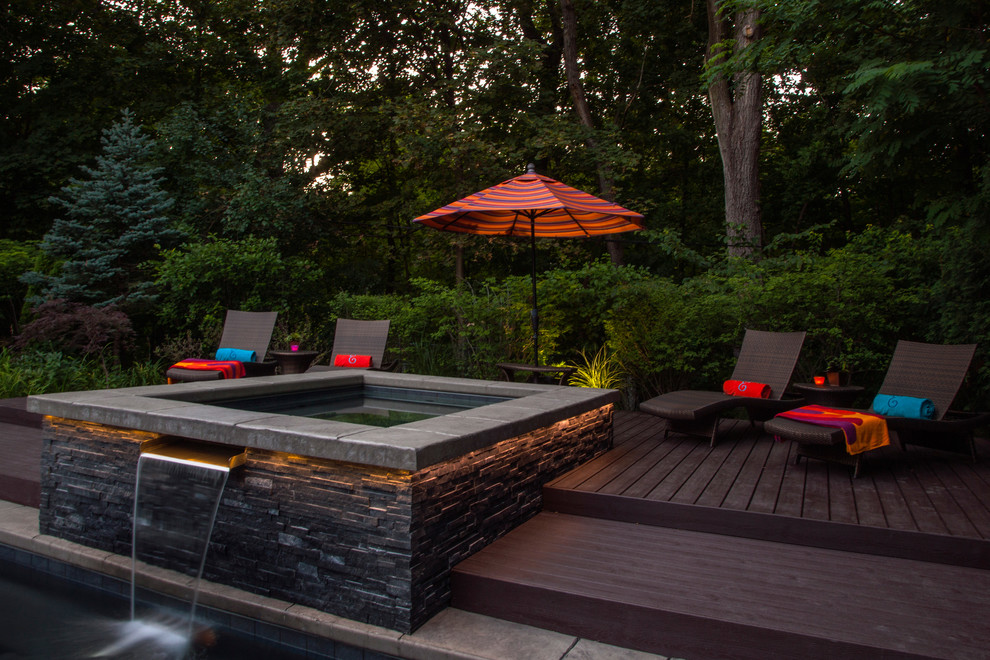 Ejemplo de piscinas y jacuzzis alargados de tamaño medio en forma de L en patio trasero con adoquines de piedra natural