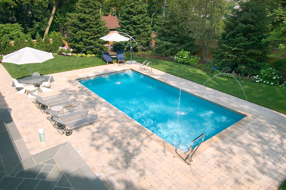 Foto de piscina con fuente alargada clásica pequeña rectangular en patio trasero con adoquines de hormigón
