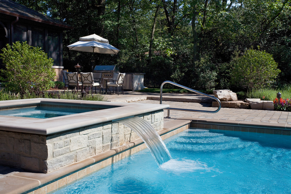 Ejemplo de piscinas y jacuzzis alargados tradicionales de tamaño medio rectangulares en patio trasero con adoquines de hormigón