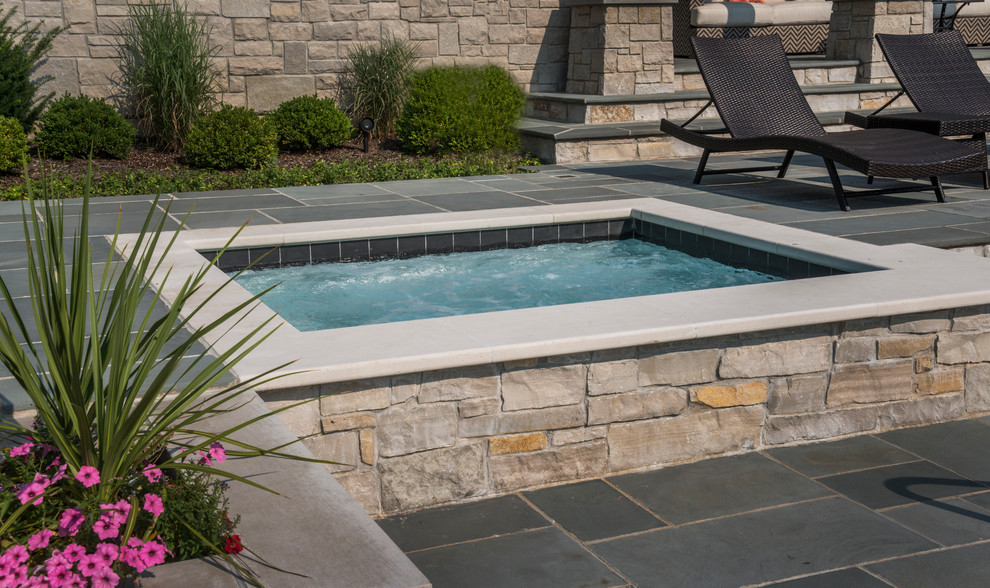 Photo of a medium sized classic back rectangular lengths hot tub in Chicago with natural stone paving.