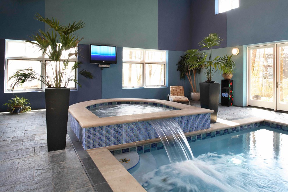 Esempio di una grande piscina coperta monocorsia minimalista rettangolare con una vasca idromassaggio e pavimentazioni in pietra naturale