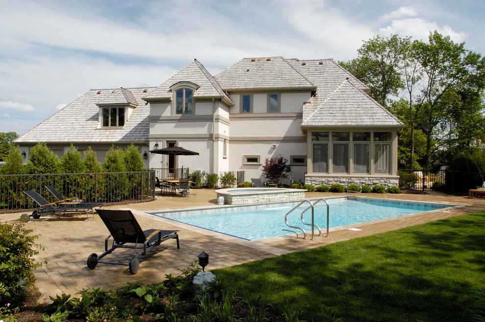 Immagine di una piscina monocorsia tradizionale rettangolare di medie dimensioni e dietro casa con pavimentazioni in cemento e una vasca idromassaggio
