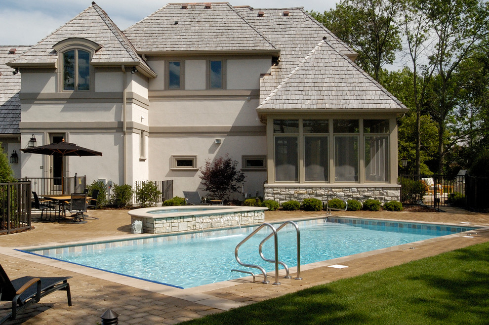Ispirazione per una piscina monocorsia tradizionale rettangolare di medie dimensioni e dietro casa con pavimentazioni in cemento e una vasca idromassaggio