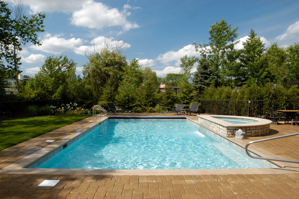 Immagine di una piscina monocorsia chic rettangolare di medie dimensioni e dietro casa con pavimentazioni in cemento e una vasca idromassaggio
