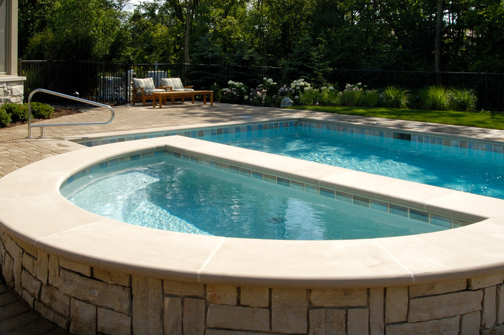 Ejemplo de piscinas y jacuzzis alargados clásicos de tamaño medio rectangulares en patio trasero con adoquines de hormigón
