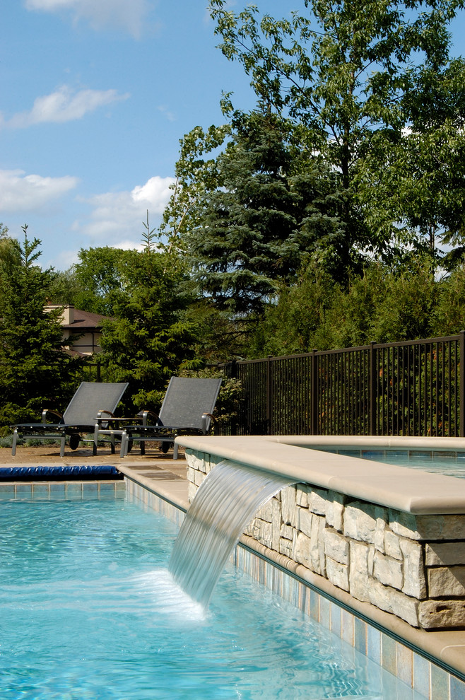 Diseño de piscinas y jacuzzis alargados clásicos de tamaño medio rectangulares en patio trasero con adoquines de hormigón