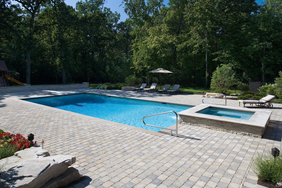 Foto de piscinas y jacuzzis alargados clásicos de tamaño medio rectangulares en patio trasero con adoquines de ladrillo