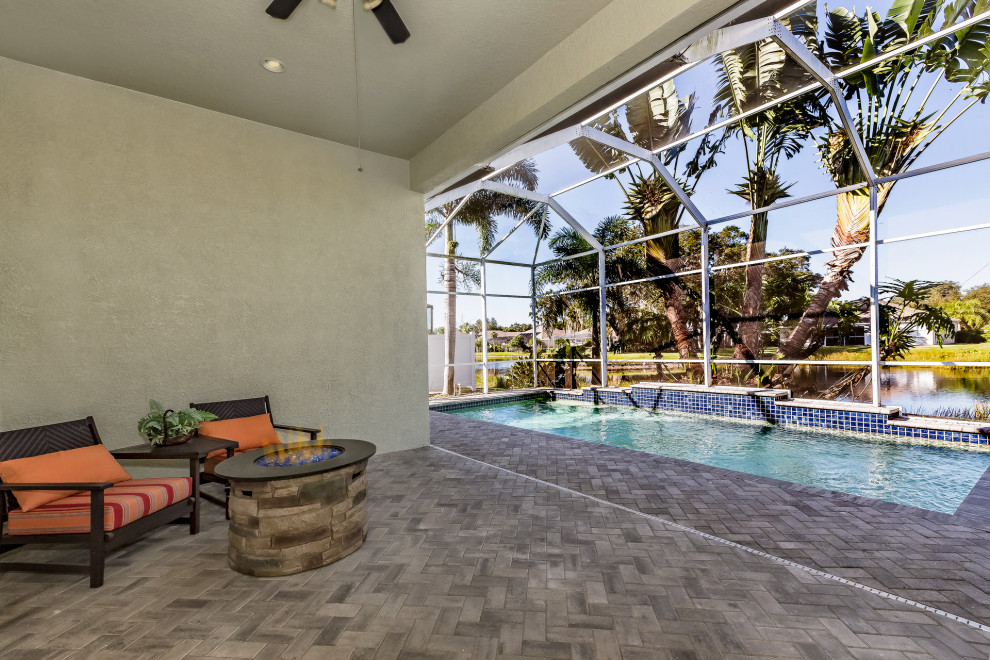 Foto de piscina natural contemporánea grande rectangular en patio trasero con adoquines de ladrillo