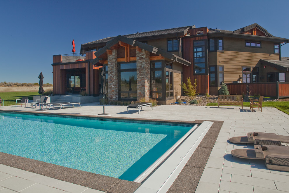 Imagen de piscina alargada de estilo americano grande rectangular en patio trasero con adoquines de hormigón