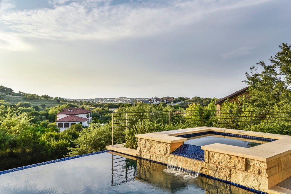 Foto di una grande piscina a sfioro infinito design rettangolare dietro casa con una vasca idromassaggio