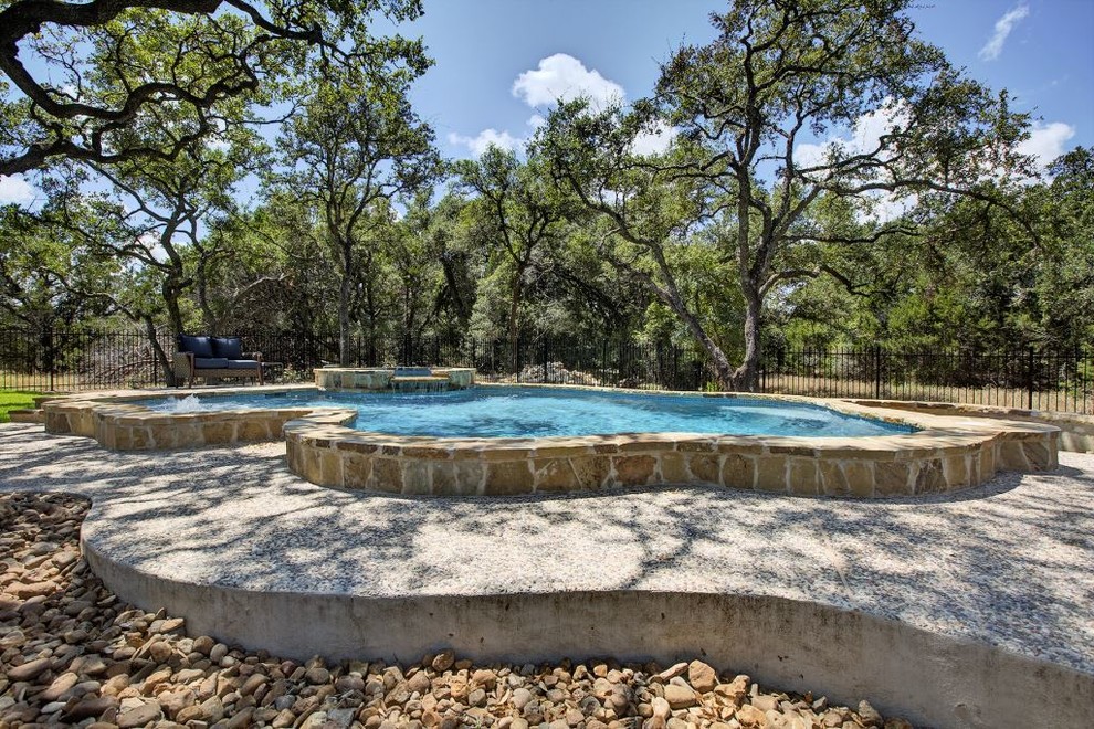 Foto di una grande piscina naturale american style personalizzata dietro casa con una vasca idromassaggio e lastre di cemento
