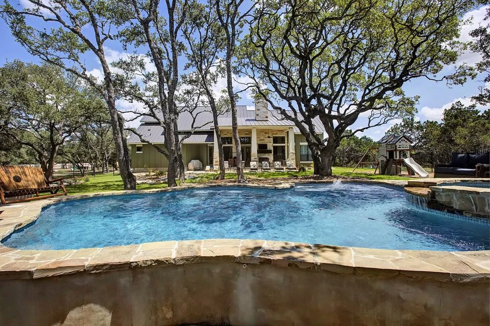 Foto di una grande piscina naturale stile americano personalizzata dietro casa con una vasca idromassaggio e lastre di cemento