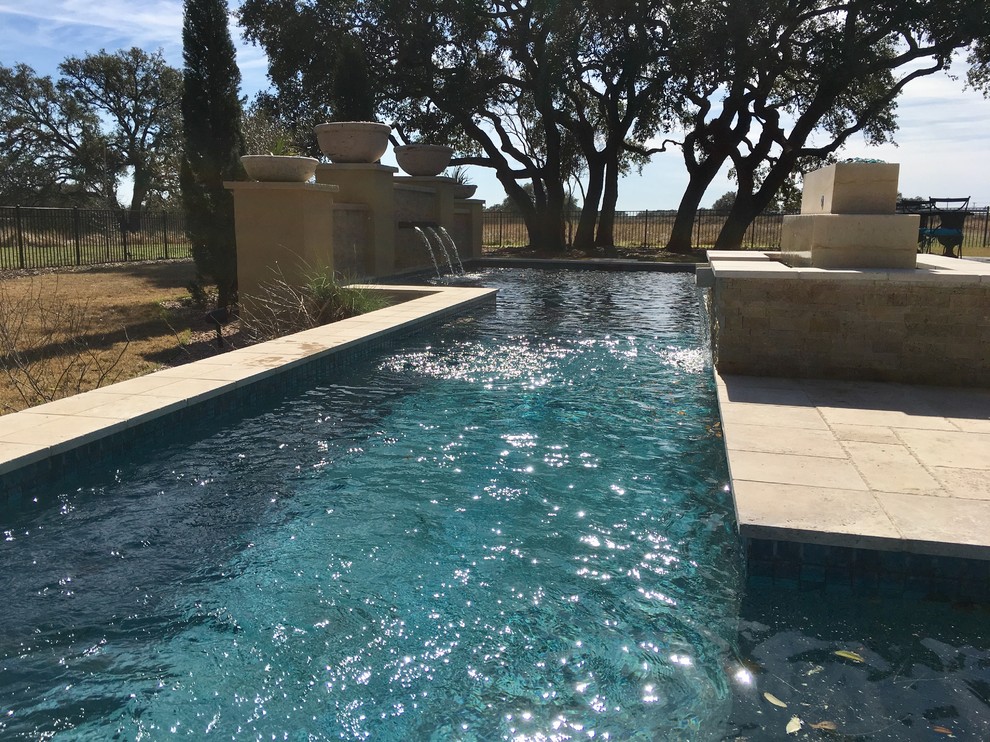 Foto di una grande piscina monocorsia contemporanea rettangolare dietro casa con una vasca idromassaggio e pavimentazioni in pietra naturale