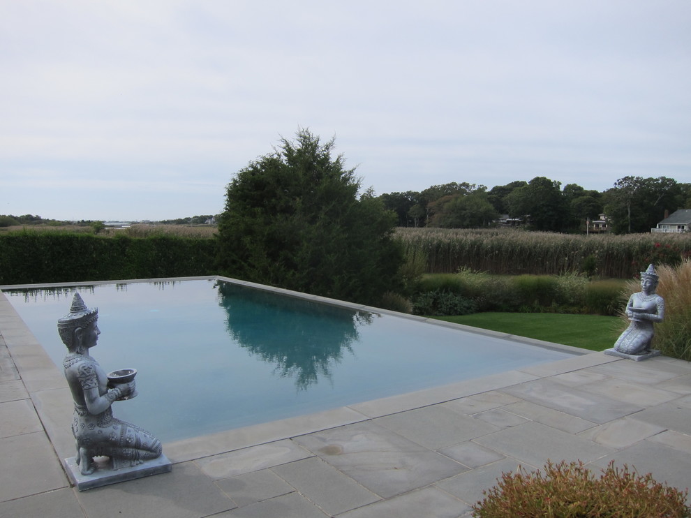Diseño de piscina de estilo zen pequeña rectangular en patio trasero con adoquines de piedra natural