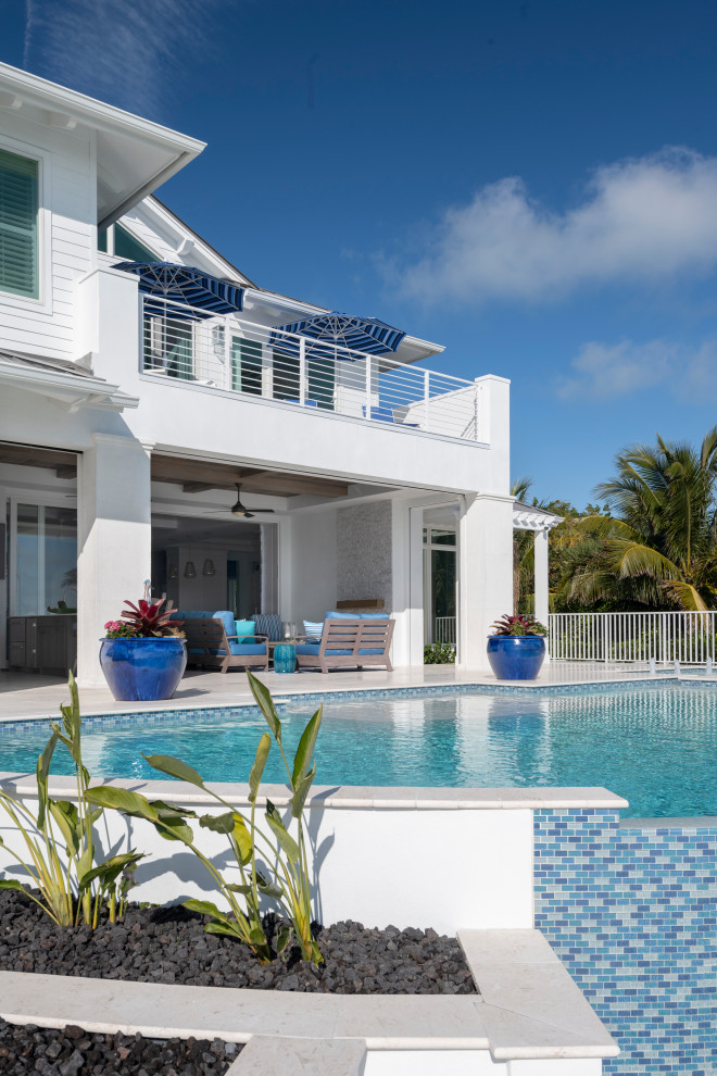 Esempio di una grande piscina a sfioro infinito stile marino personalizzata dietro casa con paesaggistica bordo piscina e piastrelle