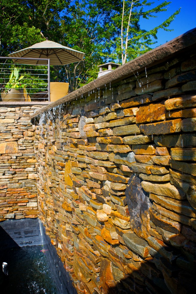 Idée de décoration pour une grande piscine à débordement et arrière tradition sur mesure avec un point d'eau et des pavés en pierre naturelle.