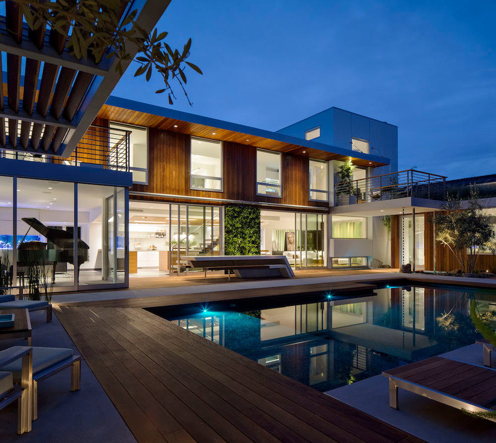 Idée de décoration pour une grande piscine design avec une terrasse en bois et une cour.