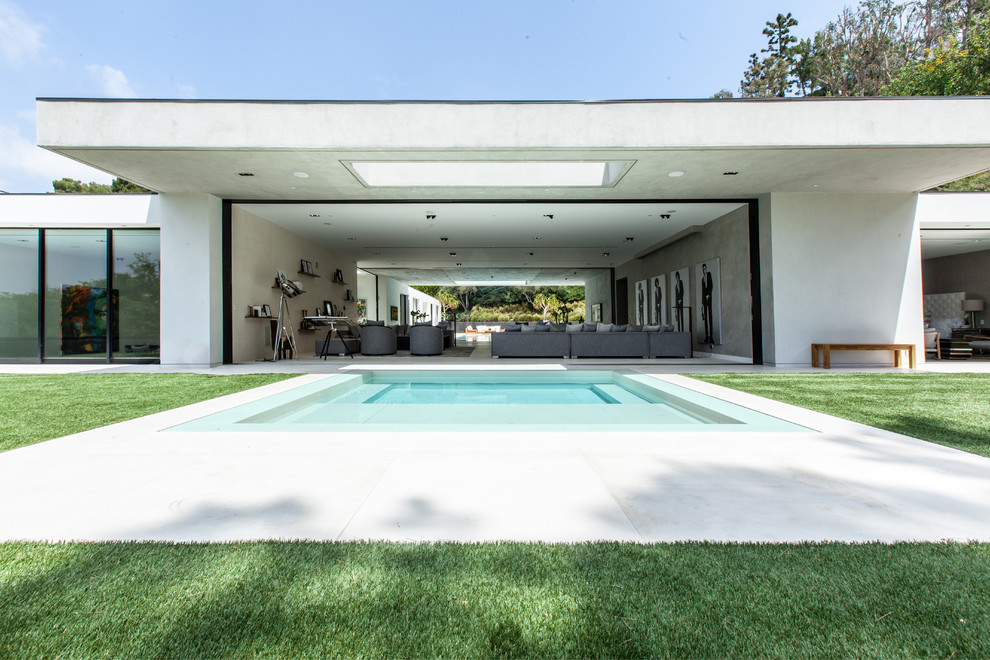 Modelo de piscinas y jacuzzis infinitos contemporáneos extra grandes rectangulares en patio trasero con losas de hormigón