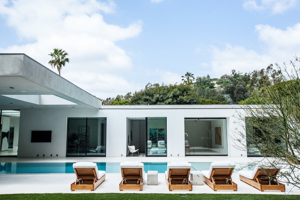 Imagen de piscina infinita contemporánea extra grande rectangular en patio trasero con losas de hormigón