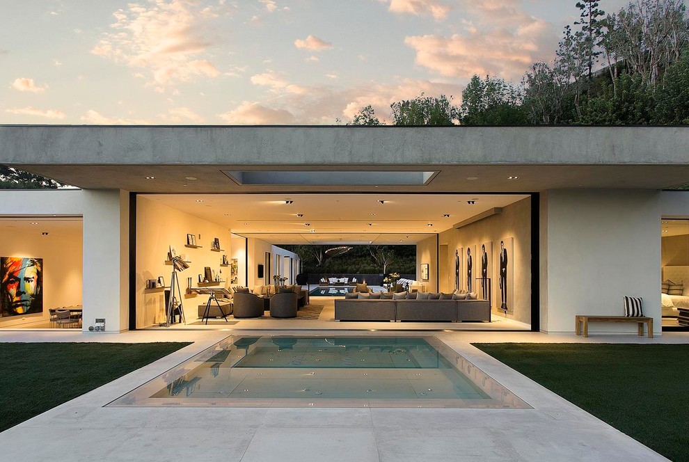 Стильный дизайн: огромный прямоугольный бассейн-инфинити на заднем дворе в современном стиле с джакузи и покрытием из бетонных плит - последний тренд