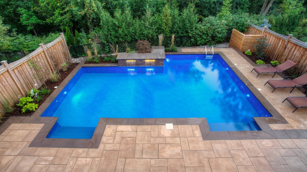 Imagen de piscina con fuente alargada minimalista de tamaño medio rectangular en patio trasero con adoquines de piedra natural