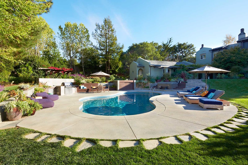 Immagine di una grande piscina design personalizzata dietro casa con lastre di cemento e una vasca idromassaggio