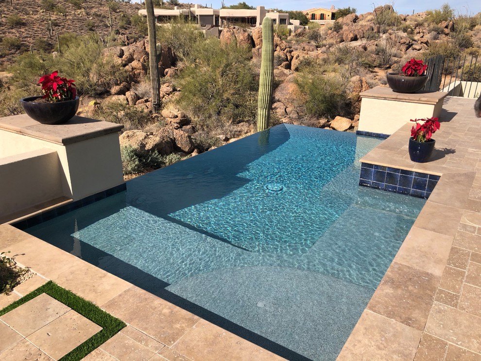 Ejemplo de piscina infinita contemporánea pequeña a medida en patio trasero con adoquines de piedra natural