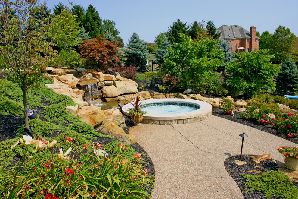 На фото: большой бассейн произвольной формы на заднем дворе в современном стиле с покрытием из бетонных плит