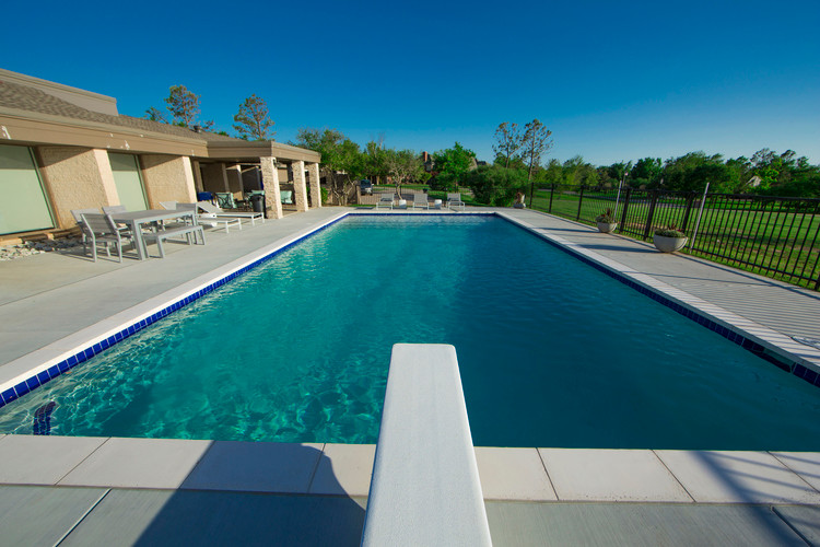 Imagen de piscina natural actual grande rectangular en patio trasero con adoquines de hormigón