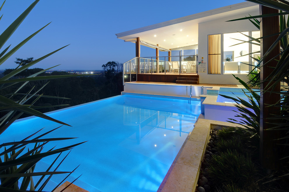 Esempio di una piscina a sfioro infinito design personalizzata di medie dimensioni e in cortile con fontane e piastrelle