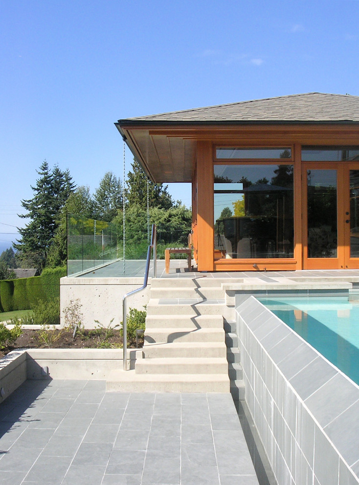 Diseño de piscinas y jacuzzis infinitos actuales grandes rectangulares en patio trasero con suelo de baldosas